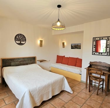 Chambre Olivier avec un grand lit, un bureau et un canapé dans une ambiance provençale. 