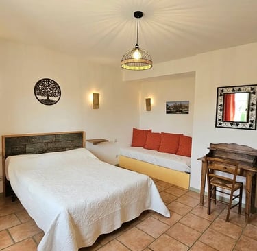 Chambre Olivier avec un grand lit, un bureau et un canapé dans une ambiance provençale. 