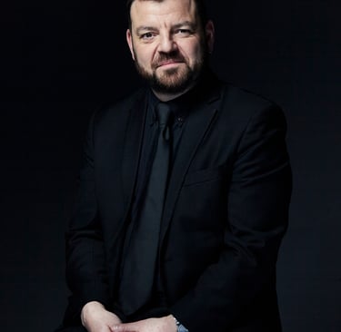 Professional portrait of Steven Devine, harpsichordist and conductor.  Black suit, shirt and tie