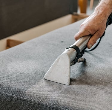 Professional upholstery cleaning sofa using a steam vacuum tool for stain removal.