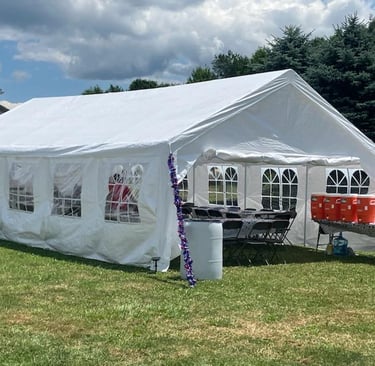 A large white event tent with windows and tables set up for an outdoor garden party on a lawn.
