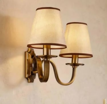 Antique brass double wall sconce fixture with two bell-shaped fabric lamp shades.