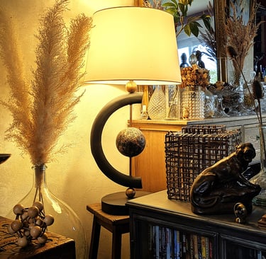 Modern black table lamp with warm glow next to pampas grass and vintage home decor accents.