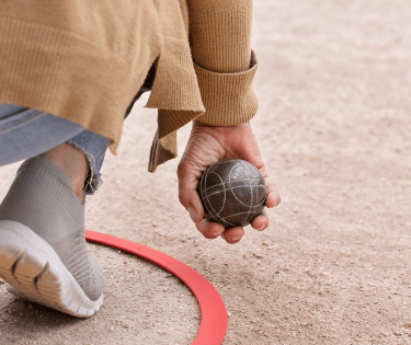 personne accroupie dans un cercle de pétanque