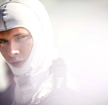 Professional race car driver wearing a white Sparco fireproof balaclava and racing suit.