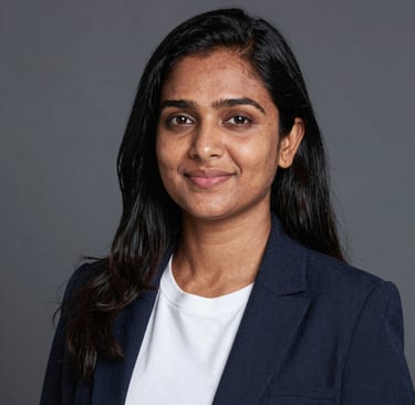 Smiling woman holding a skincare product with glowing skin in a cozy home setting