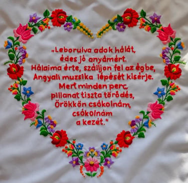 Kalocsai hímzés fehér textilen, piros hímzett szöveggel..