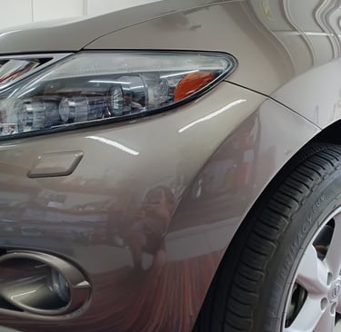 Close-up of a bronze Nissan headlight and fender after Lev Auto Refinishing.
