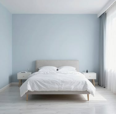 A light colored bedroom with white and soft blue tones reflecting light and making the room feel spa