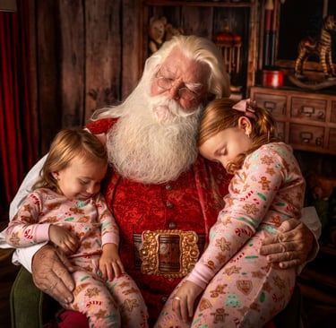 Santa Claus napping in a cozy workshop with two young girls in Christmas pajamas.