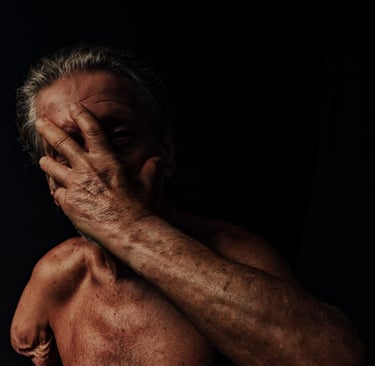 Fotografia em fundo escuro de um homem cobrindo o rosto com a mão