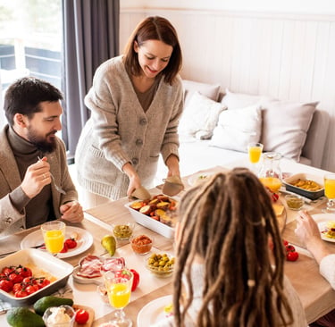 A happy family enjoys a healthy home-cooked lunch featuring roasted vegetables and fresh ingredients.