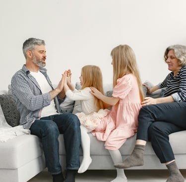 A family sitting on a couch playing games and bonding together in a bright living room.