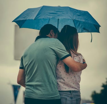 a husband and wife standing under an umbrella