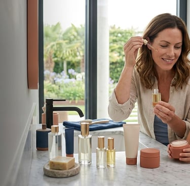 Mother and daughter applying natural skincare products and facial oils in a bright modern bathroom.