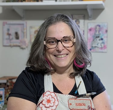 Artiste souriante portant un tablier fleuri et des lunettes dans son atelier créatif..