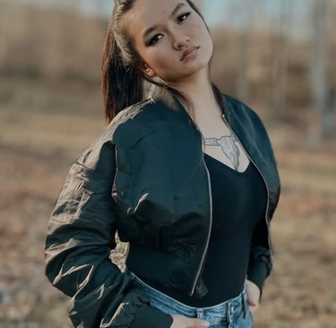 Woman in a black top with a jacket on and jeans