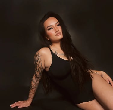 a woman in a black bodysuit and a tattoo on her arm