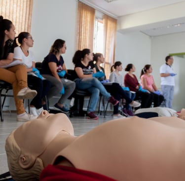Students watch a first aid demonstration with CPR mannikins during a healthcare training workshop.
