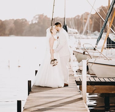 Brautpaar küsst sich auf einem Steg am Möhnesee bei Sonnenlicht – romantischer Moment eingefangen vom Hochzeitsfotografen am