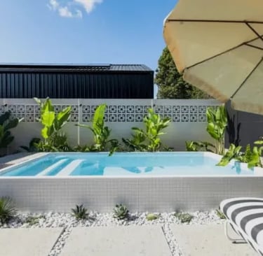 Modern raised plunge pool with pale blue water, white mosaic tiling and clean rectangular design