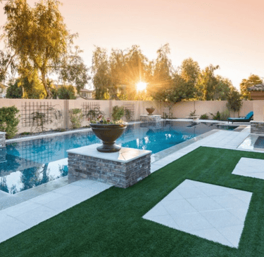 Geometric modern pool with reflective blue water and beige tiles set beneath sunset lighting
