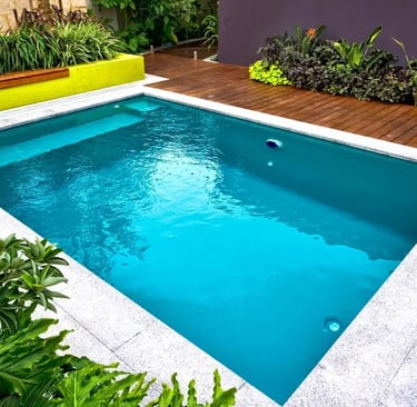 Minimalist rectangular pool with deep teal water, smooth light stone tiles and modern landscaping
