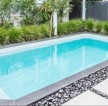 Sleek rectangular pool with light aqua water, fine white mosaic tiles and dark stone coping