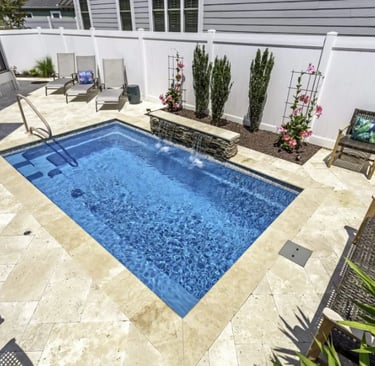 Rectangular plunge pool with clear blue water and light beige stone tiles in a classic courtyard des