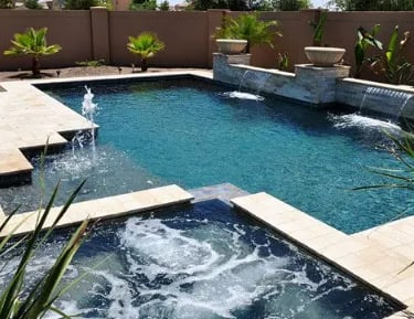 Geometric pool with teal water, beige coping tiles and raised water features.