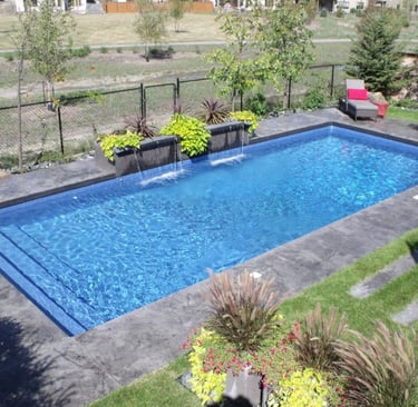 Contemporary rectangular pool with step entry, bright blue water and dark grey tiled surround.