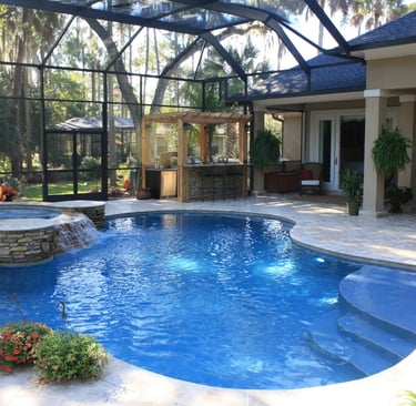 Curved resort-style pool with bright blue water and smooth blue interior, finished with pale stone p