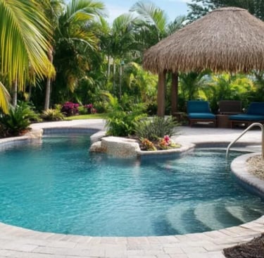 Freeform tropical pool with turquoise water and light stone coping, surrounded by lush greenery.