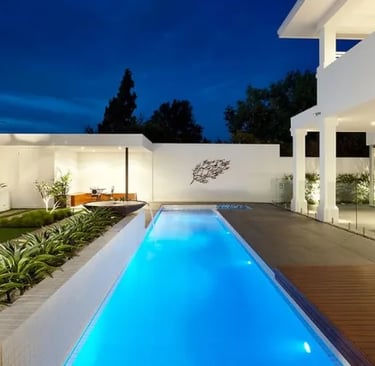 Long lap pool with clean rectangular design, glowing blue water and light mosaic tile interior.