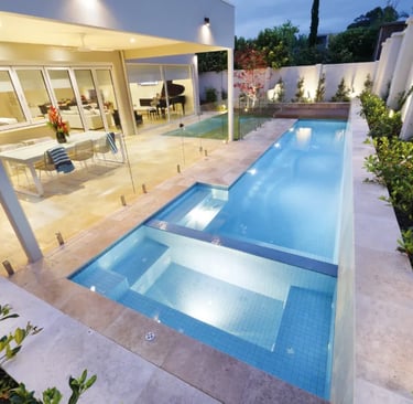 Slim contemporary lap pool, pale blue water, light blue mosaic tiles and beige stone coping