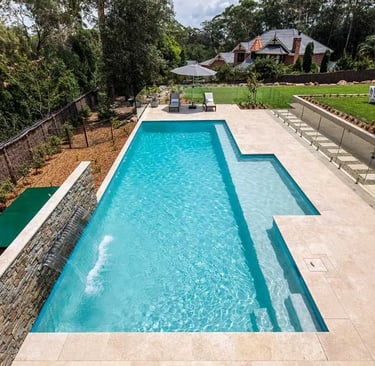 Geometric lap pool with stepped entry, clear turquoise water and pale stone tiling.