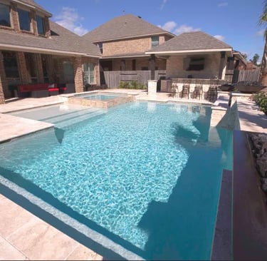Geometric pool with bright aqua water and beige travertine tiling.