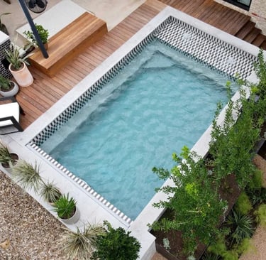 Modern rectangular pool with soft aqua water and patterned grey mosaic tiles