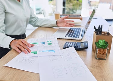 a woman sitting at a desk with a laptop and papers