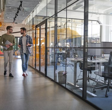 two employees walking down a hallway with a glass wall