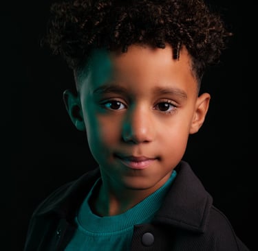 Creatief portret van een jongen van 6 jaar met ondeugende glimlach, in studiolicht met kleuren gels