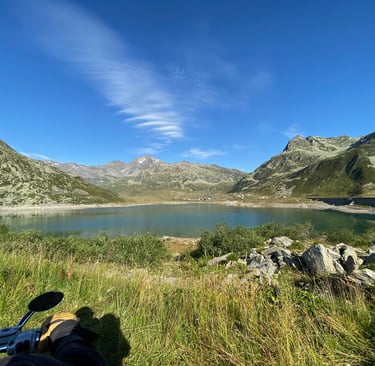 Blick auf einen malerischen Alpensee und die Berge unter strahlend blauem Himmel.