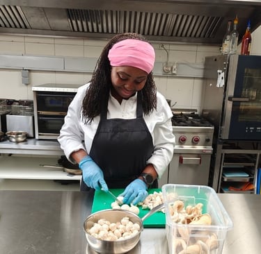Chef Viviane in white chef jacket chopping mushrooms on a green board with a bowl and prep containers.