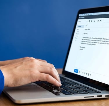 A person typing on a laptop keyboard to compose a professional email for business communication.