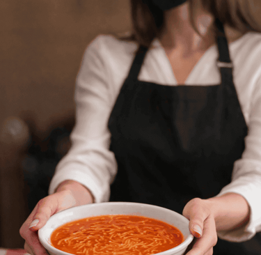 Mujer entregando plato de sopa aguada
