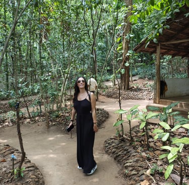 Woman in a black maxi dress walking on a jungle path at a tropical spice plantation in Goa.