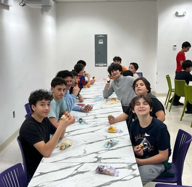 a group of students sitting at a long table enjoying ice cream and having fun