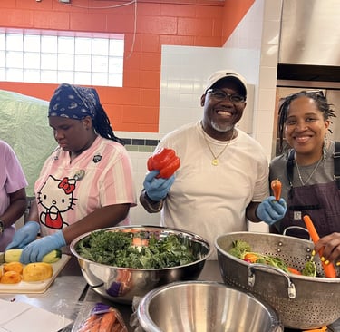 Smiling group of volunteers preparing healthy vegetables in a community kitchen.