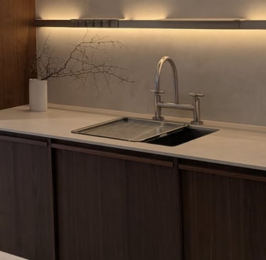 Modern minimalist kitchen with dark wood cabinets, white quartz countertop, and under-cabinet LED lighting.
