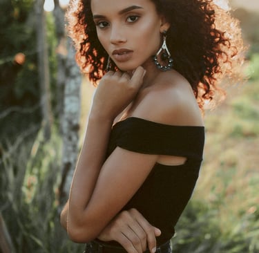 a woman with curly hair and earrings on her neck